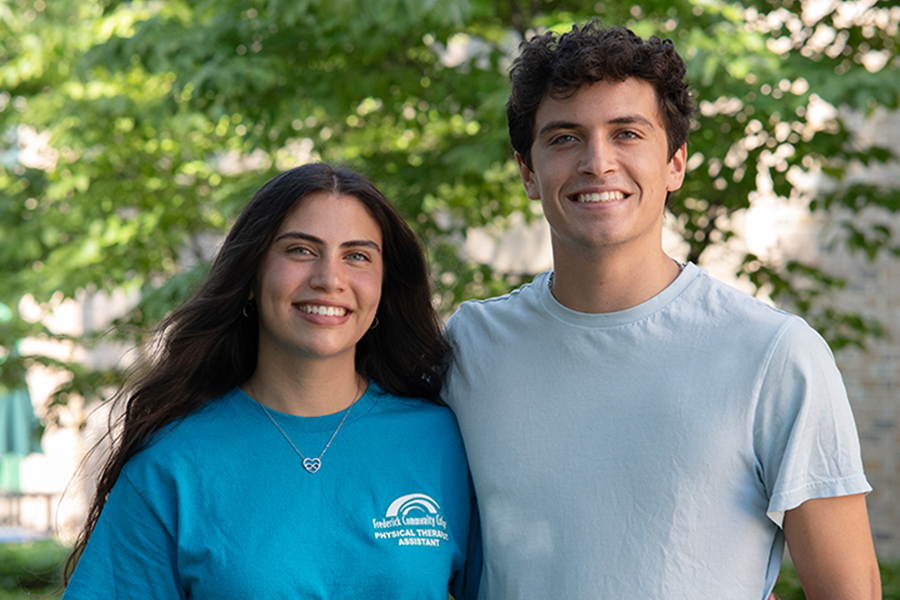two students outside smiling. 
