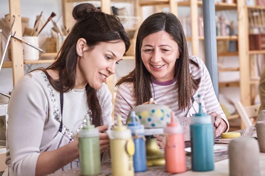 two students in an art class with paint bottles in front of them