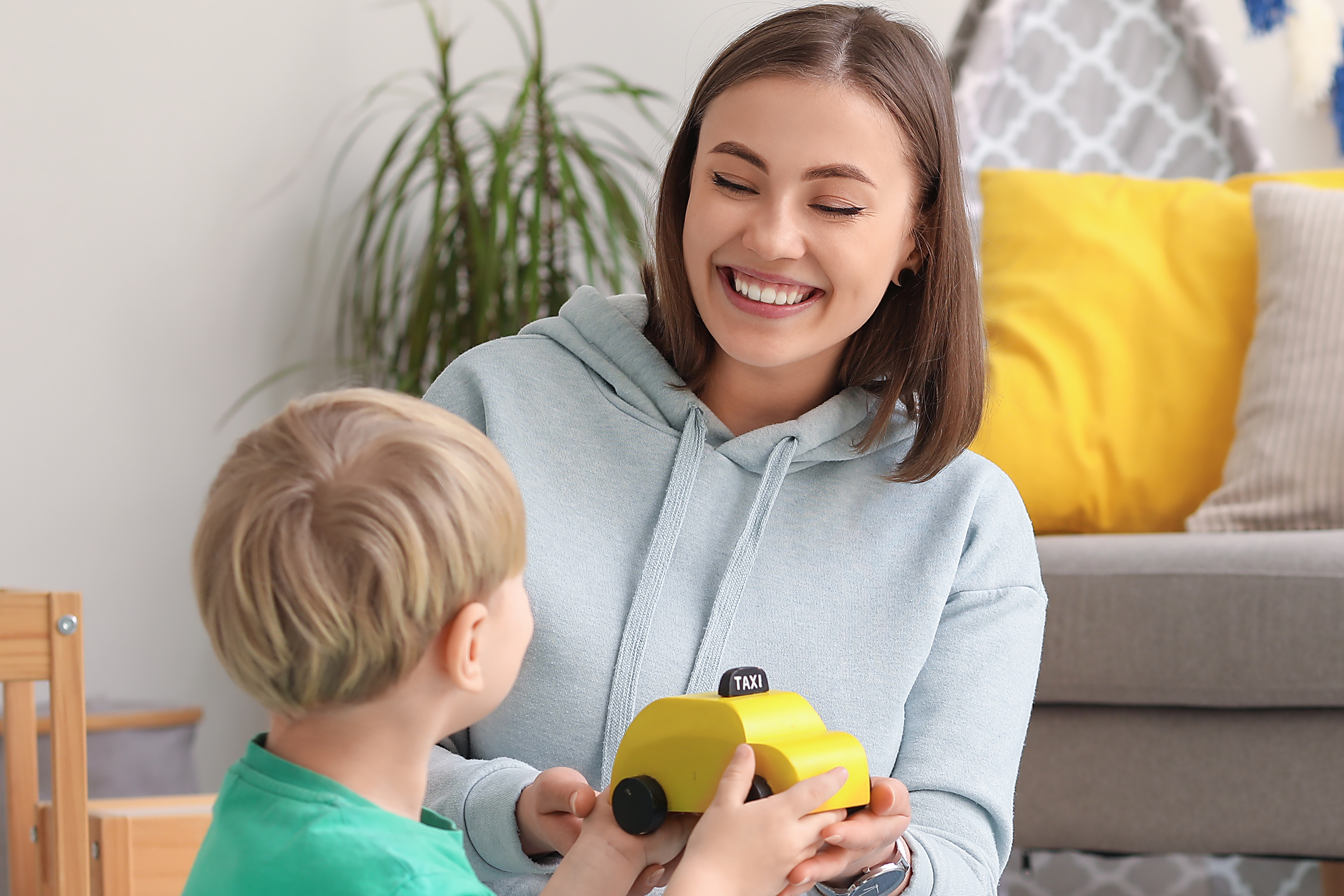 young girl holding car as she plays with toddler