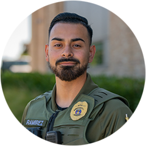 A confident campus safety officer in a green uniform poses outdoors. 